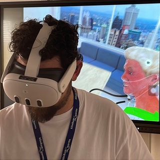 Ein Auszubildender der Pflege im Klinikum Worms trägt eine VR-Brille. Auf dem Bildschirm sieht man, was er Auszubildende in der Brille sieht.
