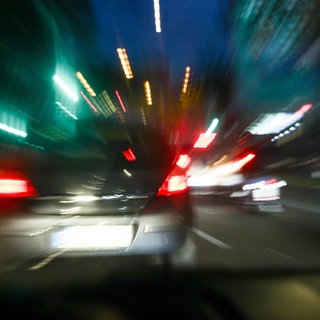 Das Symbolbild zeigt ein Auto, das nachts über eine Straße rast. 