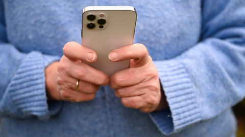 Eine Frau hält ihr Handy mit beiden Händen. Eine 50-Jährige ist in Bad Kreuznach Opfer von Love Scamming geworden.