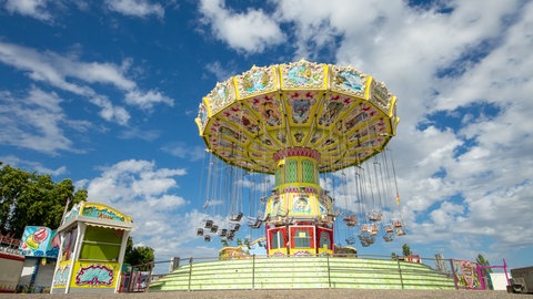 Das Kettenkarussell auf der Pfingstwiese in Bad Kreuznach. Das bunte Fahrgeschäft strahlt vor dem blauen Himmel.