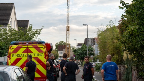 Baukran steht in einer Straße in Mainz-Laubenheim. Davor Einsatzkräfte. Der Kran droht umzustürzen. Mehrere Häuser wurden evakuiert. 