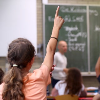 Eine Schülerin des Gymnasiums meldet sich in einem Klassenraum.