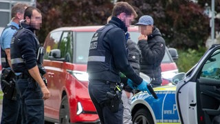 Ein Polizist hält eine täuschend echt aussehende Waffe in der Hand: In Nieder-Olm haben drei Jugendliche mit einer solchen Waffe hantiert. 