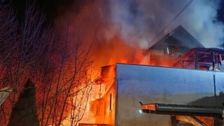 Flammen und Rauch kommen aus einem Wohnhaus: Das Feuer in Oberheimbach wurde gelegt. Das Mainzer Landgericht hat den Brandstifter zu einer Gefängnisstrafe verurteilt. 
