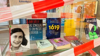 Etwa 20 Bücher stehen in einer Vitrine der Wormser Stadtbibliothek