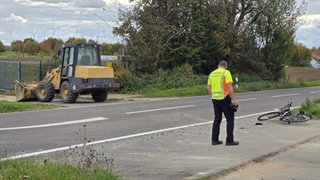 Ein Radlader und ein am Boden liegendes Fahrrad. Bei einem Unfall zwischen Lörzweiler und Nackenheim ist eine Radfahrerin von einem Radlader erfasst und tödlich verletzt worden.