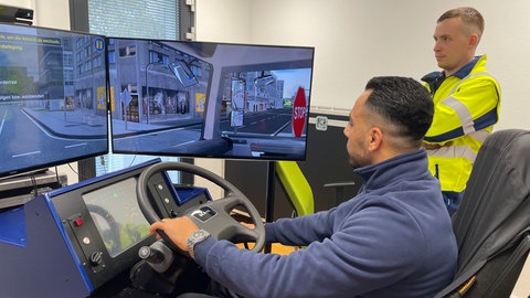 Muthana Khder sitzt in einem Fahrsimulator. Der Syrer hat in Mainz eine Ausbildung zum Busfahrer gemacht