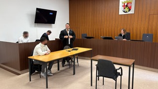 Zwei Fußballspieler sitzen mit ihren Anwälten auf der Anklagebank im Mainzer Amtsgericht. Sie müssen sich wegen einer Schlägerei verantworten.