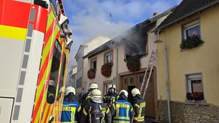 Rauch kommt aus dem Fenster eines Wohnhauses im in Schwabenheim. Davor steht ein Rettungswagen. 