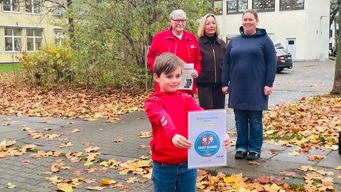 Der kleine Johannes hält die Urkunde des ACE in den Händen