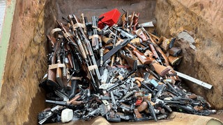 Die Waffen liegen in einem Container und sind kurz davor, zerkleinert zu werden. 
