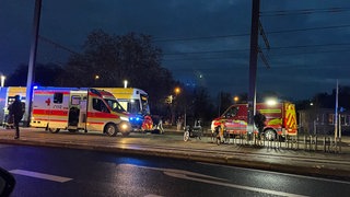 Eine Straßenbahn, ein Rettungswagen und ein Auto der Feuerwehr stehen an der Haltestelle Universität in Mainz. Jemand ist unter die Straßenbahn geraten