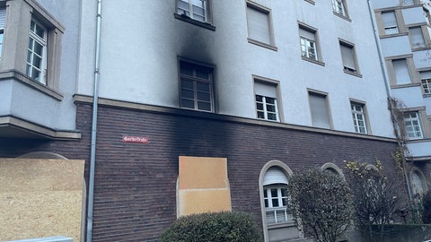 Rußspuren über einem notdürftig mit Holz verrammelten Fenster zeugen von der Explosion in einem Mainzer Mehrfamilienhaus.