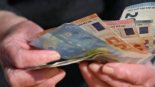 Geldscheine in der Hand eines Senioren. Der Betrüger wollte 240.000 Euro in bar mitnehmen. 