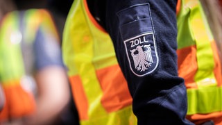 Ein Zollbeamter mit gelber Weste: Die Staatsanwaltschaft hat Anklage gegen sieben Verdächtiger aus Worms erhoben - wegen organisierter Schwarzarbit. (Symbolbild)