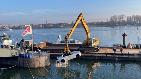 Ein Bagger mit Greifarm zieht ein Auto aus dem Rhein in Mainz. Es war am Mittwoch aus Versehen ins Wasser gerollt