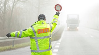 Ein Polizist winkt einen Lkw zur Kontrolle: Auf der A61 bei Zotzenheim hat die Polizei einen Lkw aus dem Verkehr gezogen, der mit 1.400 Kilo überladen war. (Symbol)