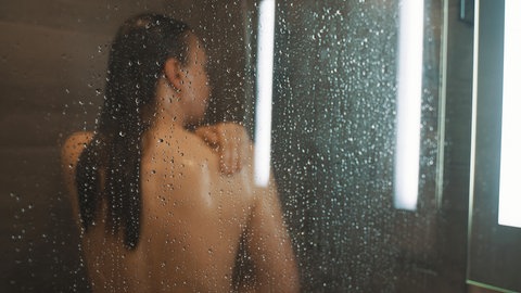 Eine Frau steht unter der Dusche (Symbolbild).