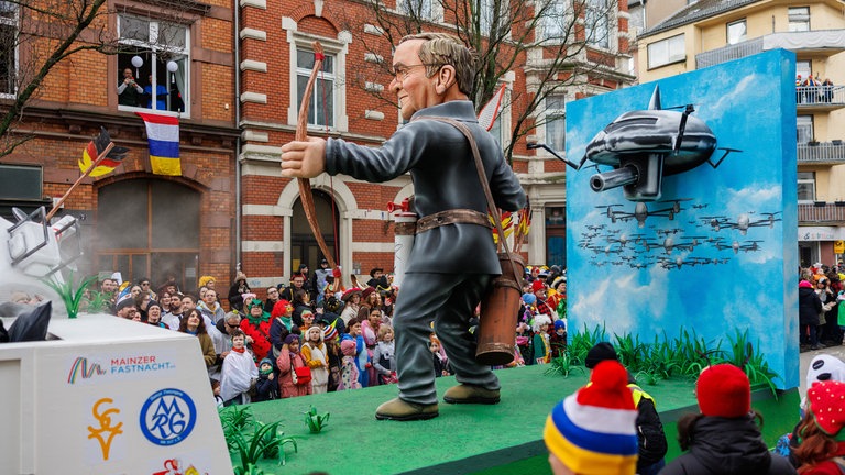 Motivwagen beim Mainzer Rosenmontagszug: Verteidigungsminister Pistorius geht mit Pfeil und Bogen auf Drohnenjagd. 