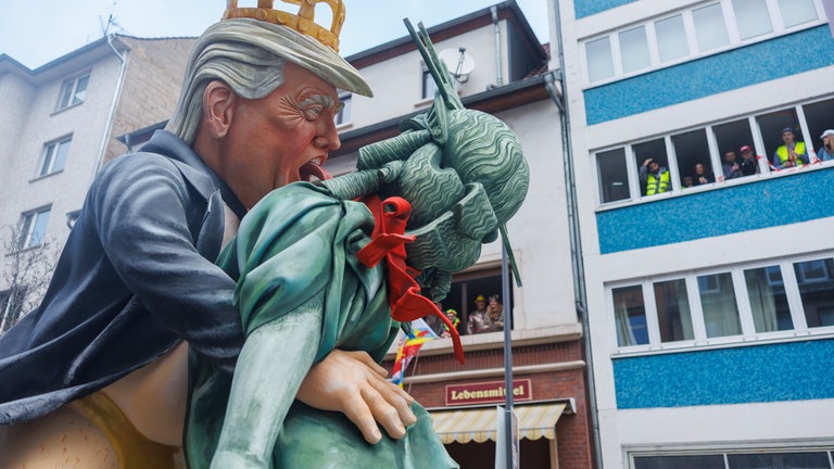 Motivwagen beim Mainzer Rosenmontagszug mit Donald Trump, der mit der Freiheitsstatue tanzt.