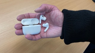 Eine Hand hält Airpods mit Case. In Mainz wurden an Rosenmontag Kopfhörer gestohlen. Per Ortung konnte der mutmaßlichen Dieb gefunden werden