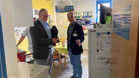 Begehung des Personalraums im Kreiskrankenhaus Alzey, in den sich die Mitarbeitenden nach dem Steinwurf geflüchtet hatten (links Thomas Busam vom Polizeipräsidium Mainz, rechts Klinikdirektor Frank Müller).