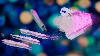 Die Droge Kokain liegt mit einer Rasierklinge auf einem Tisch.