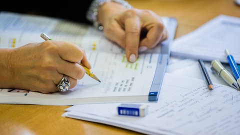 Eine Teilnehmerin schreibt in einem Deutschkurs in ein Lernbuch.