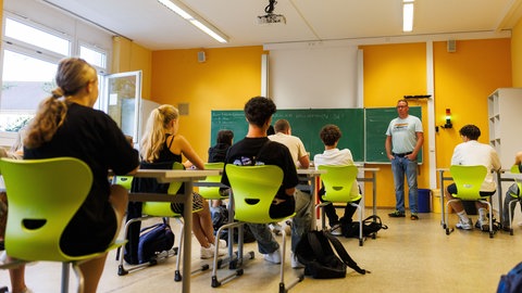 Schüler sitzen in einem Klassensaal, an der Tafel steht der Lehrer: Der Kreis Mainz-Bingen sucht einen Standort für eine neue IGS