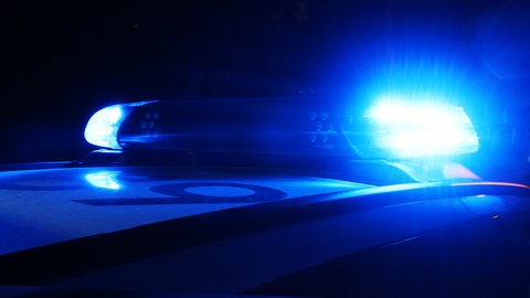 Ein Polizeiauto bei Nacht mit eingeschaltetem Blaulicht.