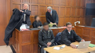Zwei Angeklagte und ihre Verteidiger vor dem Landgericht Mainz. Die beiden Männer sind wegen Brandstiftung und Erpressung angeklagt