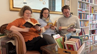 Ramona, Katrin und Dominik sitzen auf dem Sofa und lesen. Das ist der Silent Book Club von Mainz.  