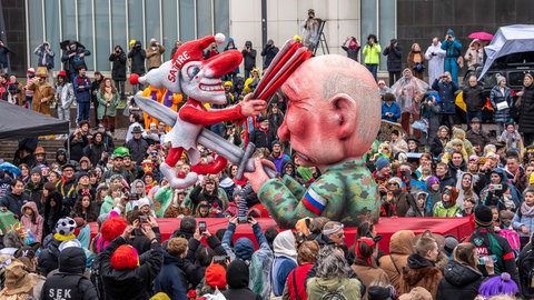 Ein Fastnachtswagen von Jacques Tilly zeigt, wie der russische Präsident Putin eine Clown-Figur mit der Aufschrift "Satire" ersticht.