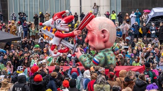 Ein Fastnachtswagen von Jacques Tilly zeigt, wie der russische Präsident Putin eine Clown-Figur mit der Aufschrift "Satire" ersticht.