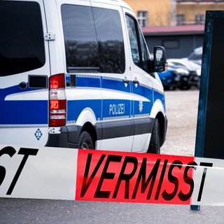 Absperrband neben einem Polizei Auto mit der Mitteilung und Polizeimeldung: Eine demente Frau aus Worms wurde vermisst. 