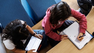 Schülerinnen bearbeiten Schulaufgaben. (Symbol) Die neue IGS für den Kreis Mainz-Bingen soll in Mommenheim gebaut werden. Das hat der Schulträgerausschuss entschieden. 