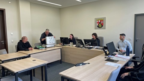 Der Angeklagte sitzt im Gerichtssaal In Bad Kreuznach, neben ihm sein Anwalt. Der Mann ist wegen fahrlässiger Brandstiftung zu einer Geldstrafe veruteilt worden. Er hatte einen Ofen illegal betrieben. 