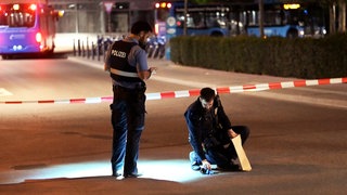 Polizisten hinter einem Absperrband, die einen verdächtigen Gegenstand eintüten. Am Wormser Hauptbahnhof hat es eine Messer-Attacke gegeben. 