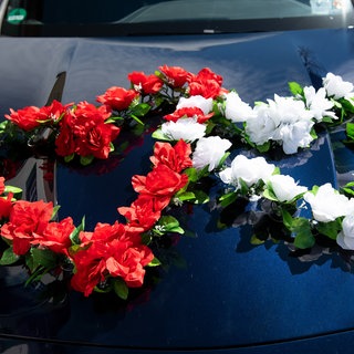 Zwei Blumenherzen schmücken eine Motorhaube. Die Polizei hat am Samstagabend einen Hochzeitskorso bei Nieder-Olm gestoppt, nachdem dieser den Verkehr massiv behindert hatte (Symbolbild).