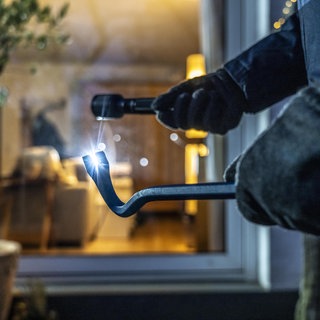 Einbrecher steht mit Brecheisen vor einem Wohnungsfenster. Drei Jugendliche sollen in Wohnung eingebrochen sein. (Symbolfoto)