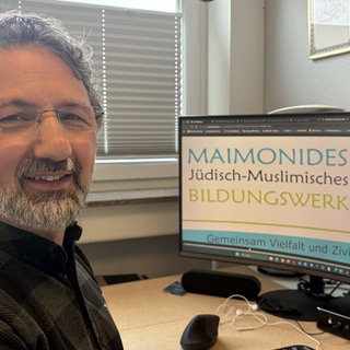 Mustafa Cimşit, Geschäftsführer von Maimonids, sitzt an seinem Schreibtisch vor seinem Computer.