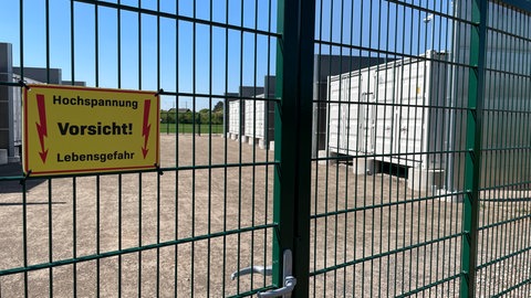 Ein Schild mit der Aufschrift: "Hochspannung. Vorsicht! Lebensgefahr." an einem Zaun, der das Wormser Batterisspeicherwerk umgrezt.