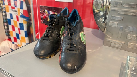 Fußballschuhe von Ex-Mainz 05-Stürmer Michael Thurk stehen in einer Glasvitrine im Landesmuseum.