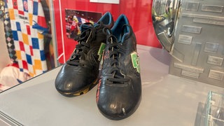 Fußballschuhe von Ex-Mainz 05-Stürmer Michael Thurk stehen in einer Glasvitrine im Landesmuseum.