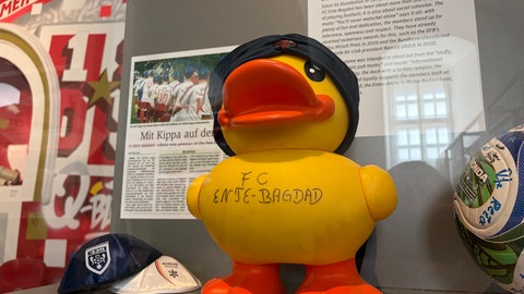 Kippas liegen in einer Vitrine neben einer Gummi-Ente des Mainzer Vereins Ente Bagdad.