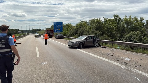 Nach einem Unfall auf der A61 bei Gau-Bickelheim steht ein Auto demoliert auf dem Seitenstreifen.