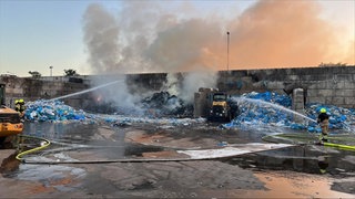 Feuerwehrleute löschen einen Brand bei einem Entsorgungsbetrieb in Worms