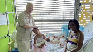 Vierlinge in einem Krankenbett im Wormser Klinikum. Dabei ihre Mutter, Schwester und ein Arzt.