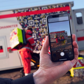 Ein Handy filmt einen Krankenwagen. In Bad Kreuznach haben Gaffer Einsatzkräft bei einem Unfall behindert. (Symbolbild)