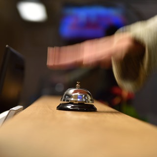 Eine Hand schlägt auf eine Rezeptionsklingel: In Mainz ist seit einem Montat die Bettensteuer in Kraft. (Symbol) 